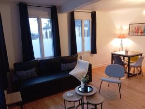 a living room with a black couch and a table at Magnifique et Grand T3 au cœur de la Normandie in Saint-Victor-lʼAbbaye