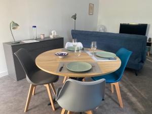 a wooden table with four chairs and a blue couch at Gîte le Taurion in Saint-Priest-Taurion +2 photos