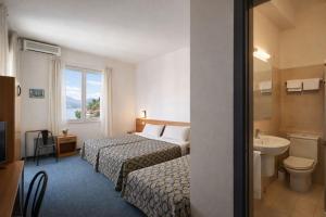 a hotel room with two beds and a sink at Hotel Granducato in Montepulciano +18 photos