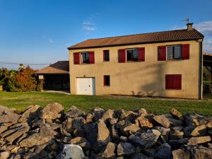 a house with red doors and a pile of rocks at Gîte Les hauts de Lenaly in Les Vans