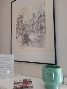a green vase sitting on a table with a painting at ATHENA Home Asti in Asti