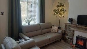 a living room with a couch and a fireplace at Harrys Hideaway Cottage in Haworth