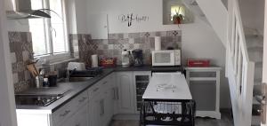 a kitchen with white cabinets and a microwave at La maison de poupées in Bourseul