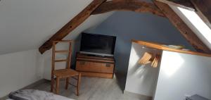a room with a tv and a ladder and a chair at La maison de poupées in Bourseul