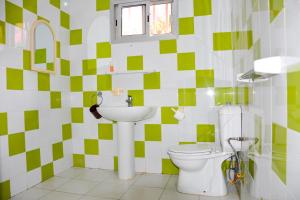 a green and white bathroom with a toilet and a sink at Résidence KEUR FLEURIE in Rufisque