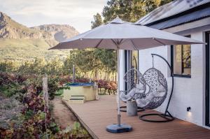 a patio with an umbrella and a chair on a deck at Genadendaal Vineyard Villa in Paarl