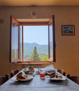 a table with plates of food and a large window at Hotel Monte Viglio in Filettino