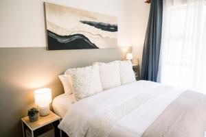 a bedroom with a white bed and a painting on the wall at The Halfway Homestead in Middelburg