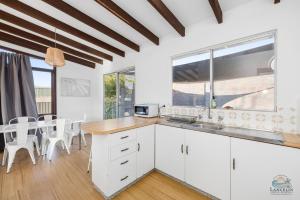 a kitchen with white cabinets and a table and chairs at Sea Gem in Lancelin +14 photos