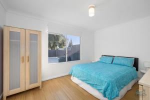 a white bedroom with a bed and a window at Sea Gem in Lancelin