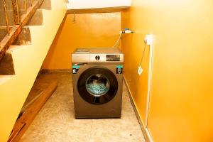 a washing machine in a laundry room with an orange wall at 21 Suites & Apartments in Mama
