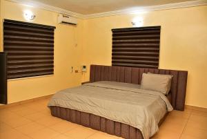 a bedroom with a bed and two windows with blinds at 21 Suites & Apartments in Mama