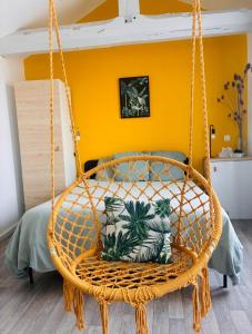 a wicker swing in a bedroom with a yellow wall at Chez Mary Studio -Jungle in Gannat