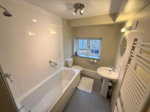 a bathroom with a tub and a toilet and a sink at The Old Mill Inn in Bedford