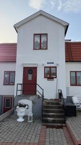 a white house with a red door and stairs at Dahlias Bed & Breakfast in Väderstad