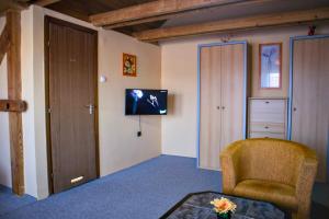 a living room with a chair and a tv on the wall at Fehérló Vendégház & Restaurant in Bük