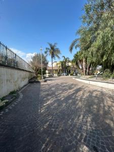 a cobblestone street with palm trees and a fence at Martone house in Castellammare di Stabia