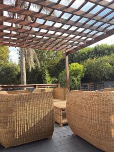 a patio with wicker chairs and a wooden pergola at 101 Marais Villa in Hartbeespoort