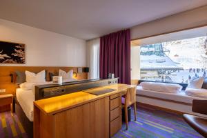 a hotel room with a bed and a desk and a window at Quality Hosts Arlberg - Hotel ANTON in Sankt Anton am Arlberg
