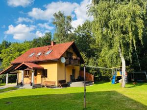 a yellow house with a red roof and a playground at Domek nad Wisłą in Ustroń