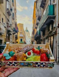 a person holding a box of fruit and pastries at Matri Mia in Trapani