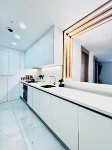 a kitchen with white cabinets and a large mirror at Zen Living Sky Suite in SamborondÃ³n