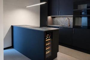 a kitchen with a blue island with wine bottles at Studio 28 in Narvik