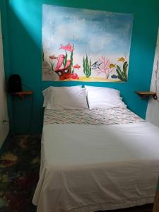 a bedroom with a bed with a painting on the wall at Casa hostal playa coral in Capurganá