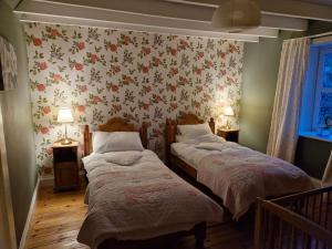two beds in a room with floral wallpaper at Barcloy Milk House in Kirkcudbright