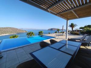 a patio with a table and chairs and a swimming pool at Villa Tholos Crete in Kavoúsion