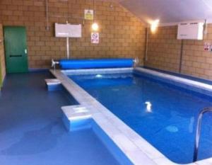 a large swimming pool with blue water in a building at Ailsa Seaview in Turnberry