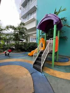 a playground with a slide and an umbrella at Hailey's Place Unit 3 in Bacolod