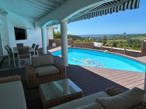 a house with a swimming pool with a table and chairs at Domaine Madinina Dream in Sainte-Luce