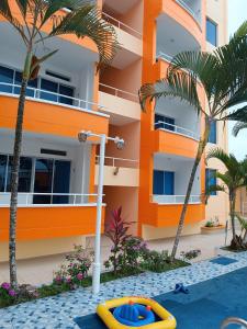 an orange building with palm trees and a pool at Departamento impecable en Tonsupa, Conjunto Vacacional Salaverry VI in Tonsupa