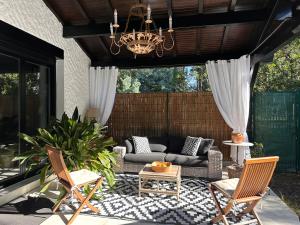 a patio with a couch and chairs and a chandelier at La Becada de las Landas in Seignosse