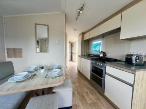 a kitchen with a wooden table and a kitchen with a counter at Seaside Caravan in a Leisure Park with WiFi & Parking - 3 bedrooms in Meliden