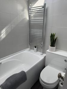 a white bathroom with a toilet and a bath tub at Spacious 3BR Flat near Newcastle Centre in Saint Peters