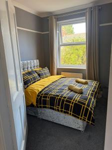 a bedroom with a yellow and blue bed with a window at Spacious 3BR Flat near Newcastle Centre in Saint Peters +10 photos