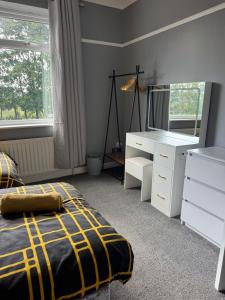 a bedroom with a bed and a dresser and a mirror at Spacious 3BR Flat near Newcastle Centre in Saint Peters