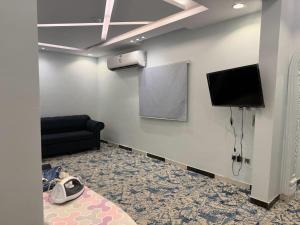 a waiting room with a black couch and a tv at Dar Al-Areed in Medina