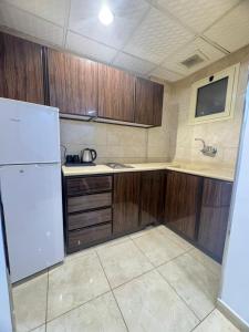 a kitchen with wooden cabinets and a white refrigerator at عز الاصالة للشقق المخدومة تصنيف اقتصادي in Taif