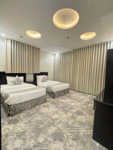 a hotel room with two beds and a television at عز الاصالة للشقق المخدومة تصنيف اقتصادي in Taif