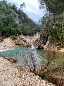 a river with a waterfall in the middle of a mountain at El Refugio de la montaña in Arroyo Frio