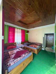 two beds in a bedroom with a wooden ceiling at SOUPRIYA Impression Homestay in Pedong
