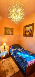 a bedroom with a blue bed and a chandelier at B&B Margot in Albavilla +81 photos