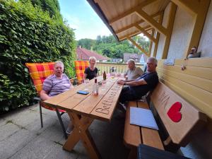 a group of people sitting at a wooden table at Kleines Glück am Bärenstein in Gößweinstein