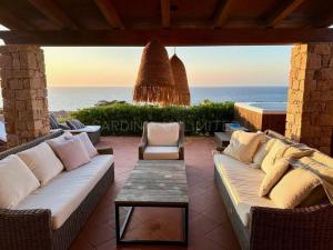a patio with couches and a table and the ocean at Li Junchi in Costa Paradiso