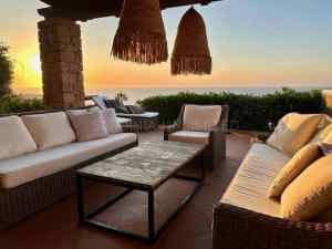a patio with a couch and chairs and a table at Li Junchi in Costa Paradiso
