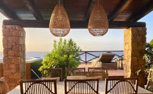 a patio with chairs and chandeliers and the ocean at Li Junchi in Costa Paradiso