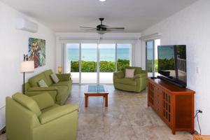 a living room with two green chairs and a television at Casa Portofino in Chuburná